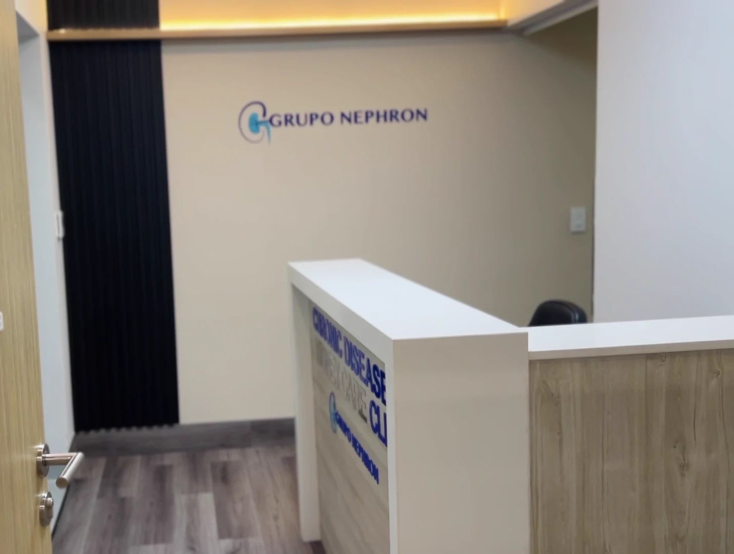 Recepción real de Grupo Nephron con mostrador de madera clara y el nombre de la clínica en la pared.